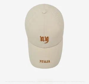 Detail view of breathable laser-cut holes and brown NY embroidery on beige baseball cap