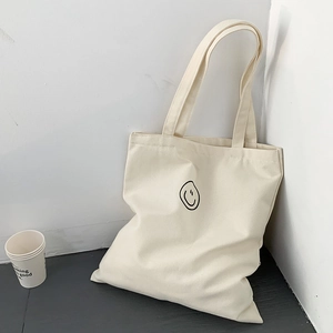 Minimalist beige canvas tote bag with black line art smiley face for students