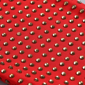 Detailed macro view of red mesh fabric with sparkling gold rhinestones and metallic studs