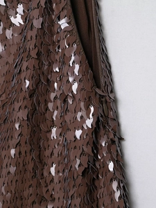 Vue macro du tissu à paillettes marron avec motifs feuilles et fermeture éclair invisible