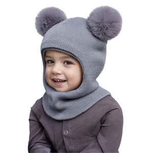 Close-up of grey knit baby balaclava featuring double faux fur pom-poms and ribbed texture