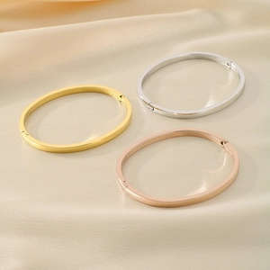 Minimalist oval open bangles in gold, silver, and rose gold on elegant silk fabric