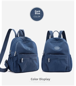Detail view of a navy blue nylon backpack featuring side elastic pockets and front zip