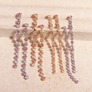 Close-up of pink and white zircon stones on gold and silver tassel earrings displayed