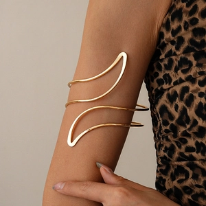 Close-up of golden wavy arm cuff with a double-layered minimalist metallic design