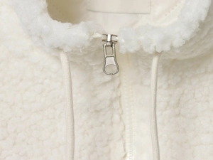 Close-up of white lamb wool jacket featuring a metal zipper and woven drawstring details