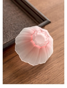 Detailed top view of pink gradient lotus-shaped frosted glass tea cup on wooden tray