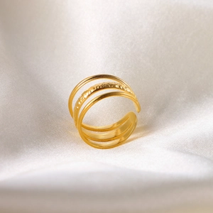 Detailed view of triple-layered 18k gold plated stainless steel ring on white silk