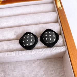 Detail shot of vintage black fabric earrings with white polka dots in a beige jewelry box