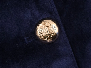 Macro detail of golden embossed buttons on dark blue velvet fabric of women suit