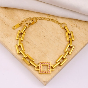 Detailed close-up of a gold bracelet with a pink crystal inlay on marble and silk background