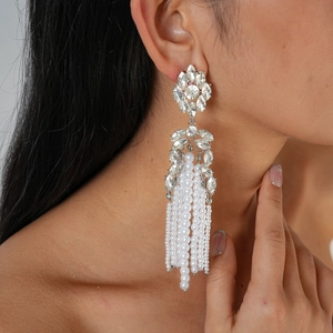Détail de boucles d'oreilles fleurs en strass avec de longs glands en perles