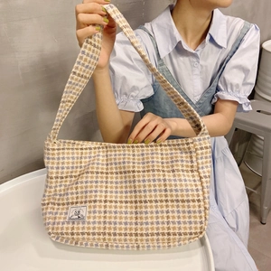 Close-up of woven tweed shoulder bag with navy checkered pattern and brand label detail