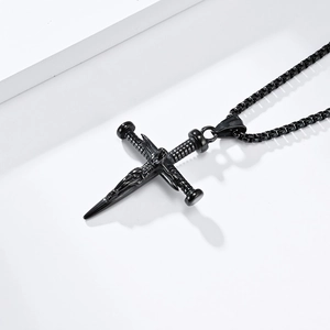 Detail of vintage black stainless steel cross pendant with intricate gothic carvings and bead chain