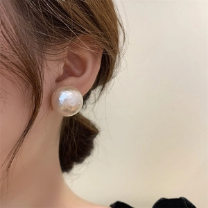Gros plan d'une grande boucle d'oreille en perle mate au lustre irisé élégant
