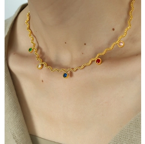 Close-up of golden wave necklace featuring five multicolored round cut zircon gemstones