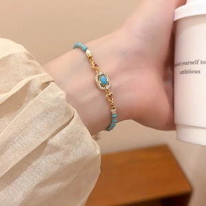 Detail of vintage beaded bracelet with turquoise stones on model's wrist with coffee cup