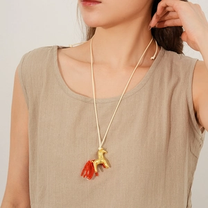 Détail du collier pendentif poney doré avec queue en perles rouges sur cordon beige