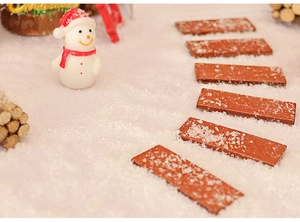 Miniature Christmas landscape detail with artificial snow, wooden stairs, and a tiny snowman