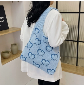 Sac fourre-tout en tricot bleu avec motif coeur porté à l'épaule pour un look chic