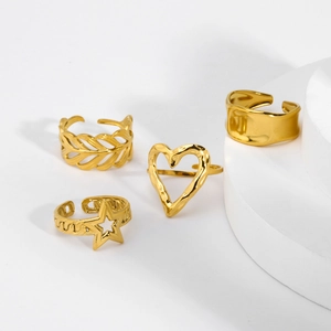Detail of four adjustable gold stainless steel rings with heart, leaf, and star patterns