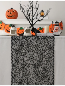 Detail of black lace spider web table runner set against a festive Halloween fireplace