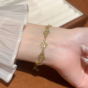 Detail of a gold-toned hollow cloud charm bracelet with an adjustable lobster clasp closure
