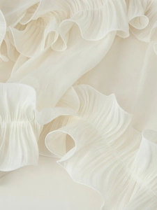 Detailed macro view of layered white chiffon ruffles and pleated fabric texture on dress