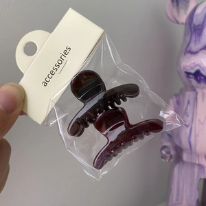 Close-up of two mini amber hair clips packed in a transparent bag with accessories tag