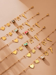 Detail of gold beaded bracelets with colorful enamel heart and clover charms