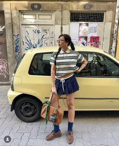 Dettaglio della polo stile preppy vintage con colletto a righe e borsa in pelle
