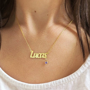 Detailed view of custom gold Lucas name necklace with a purple birthstone on model