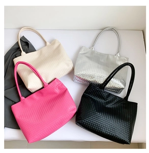Flat lay of large woven leather tote bags in cream, silver, pink, and black colors