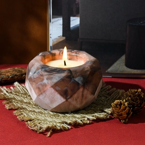 Detailed view of burning candle in geometric facet mold on vintage rustic burlap base