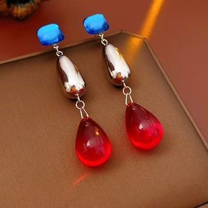 Close-up of vintage long tassel earrings with blue square and red teardrop resin parts