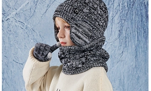 Close-up of children's thick knit hat, scarf and touch-screen gloves in winter forest