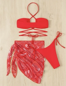 Flat lay of red three-piece bikini set including mesh sarong with marble pattern
