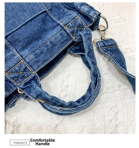 Detail view of reinforced denim bag handles with orange stitching and metal hardware