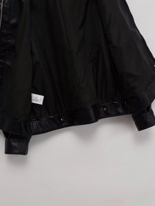Détail d'une veste en cuir noir montrant la doublure intérieure et la boucle en métal