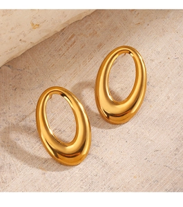Detail of golden geometric oval stud earrings on textured beige stone background