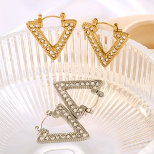 Minimalist V-shaped geometric gold and silver stud earrings with crystals in a glass bowl