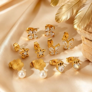 Gold stainless steel earring set with butterfly, star, and flower studs on champagne silk