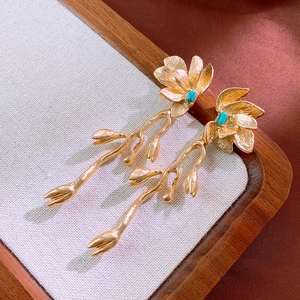 Détail de boucles d'oreilles fleuries avec pierres turquoise sur soie élégante