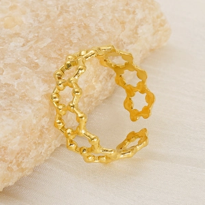Bague ajustable dorée en acier titane avec motif alvéolé sur un support en pierre