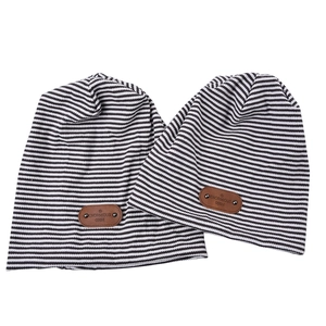 Striped knit beanie with leather patch in black and white pattern on white background
