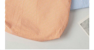 Detailed texture of seersucker cosmetic bag showing orange and blue striped fabric