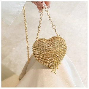 Macro view of a gold heart-shaped evening bag with crystals and tassel fringe details