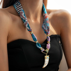 Detail of bohemian ivory elephant tusk pendant with blue evil eye and colorful silk fabric
