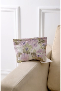 Détail de la trousse de maquillage jacquard à fleurs violet et or avec étiquette