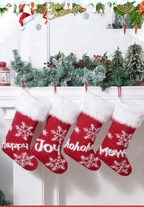 Close-up of four red knit Christmas stockings with white snowflakes hanging on a fireplace